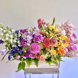Colorful mixed flower arrangement in a wooden box on a stand