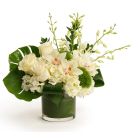 White floral arrangement in a green glass vase with orchids and roses