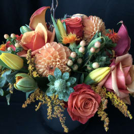Mixed bouquet with roses, calla lilies, dahlias, and tulips in a dark vase