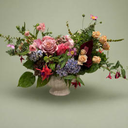 Mixed bouquet of pink and peach flowers in a white vase