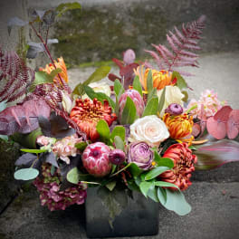 Mixed bouquet in a black vase with orange, pink, and white blooms