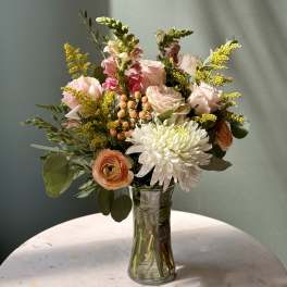 Mixed bouquet of pale pink and white flowers in a clear glass vase