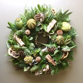 Green holiday wreath with pinecones, dried citrus, and cinnamon sticks