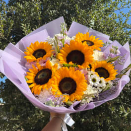 Bouquet of sunflowers and pastel flowers wrapped in lavender paper