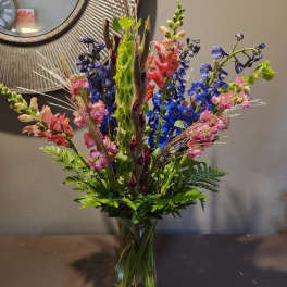Tall mixed bouquet in a glass vase with blue and pink flowers