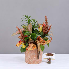 Autumn arrangement in a patterned ceramic pot with ribbon and mixed foliage