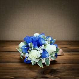 White rose bouquet with blue ribbon loops on a wooden surface
