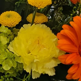 Close-up of yellow, orange, and green flowers in a mixed bouquet