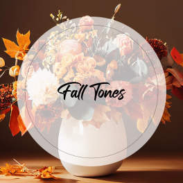 Fall-toned bouquet in a white vase with orange and cream flowers