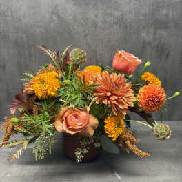 Orange and peach mixed bouquet in a dark vase