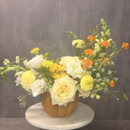 Yellow and white floral arrangement in a pumpkin-shaped vase