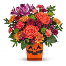 Bouquet of orange and purple flowers in a jack-o'-lantern vase