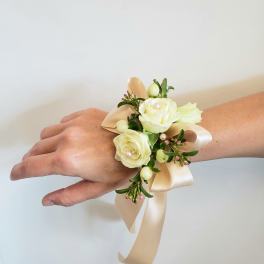 Cream rose wrist corsage with ribbon on a person's wrist