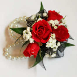 Red rose corsage with white filler flowers and pearl bracelet