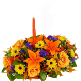 Orange and yellow floral centerpiece with a tall orange candle