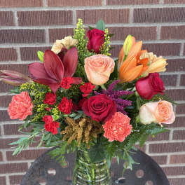 Mixed bouquet of roses, lilies, and carnations in a glass vase