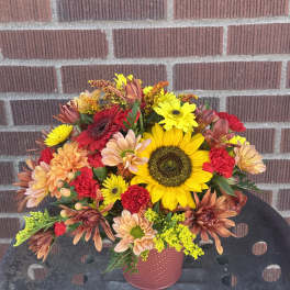 Mixed bouquet with sunflowers, daisies, and carnations in a pink vase