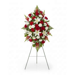 Standing floral spray with red roses, white lilies, and white daisies on an easel