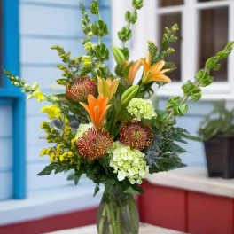 Mixed bouquet with orange lilies and green hydrangeas in a glass vase