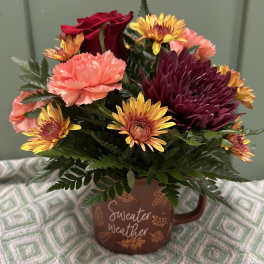 Bouquet of red roses, carnations, and chrysanthemums in a brown mug vase