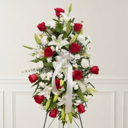 Standing floral spray with red roses, white lilies, and a white ribbon