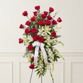 Tall standing floral spray with red roses, white lilies, and a white ribbon