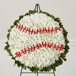 Round white chrysanthemum wreath with red ribbon accents on a stand
