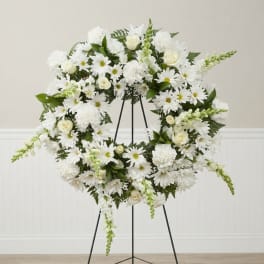 White floral wreath on a black easel stand