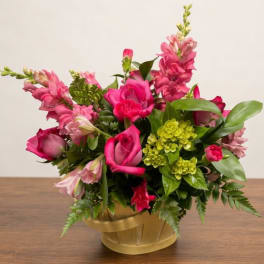 Pink roses and snapdragons arranged in a gold basket