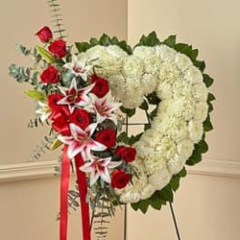 Heart-shaped floral wreath with red roses and white blooms on an easel