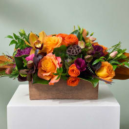 Orange and purple floral arrangement in a wooden box
