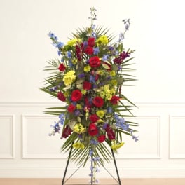 Tall standing floral spray with red roses, blue flowers, and yellow blooms