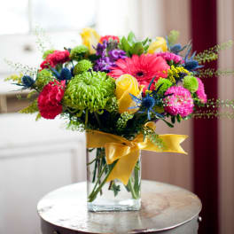 Colorful bouquet in a clear glass vase with a yellow ribbon
