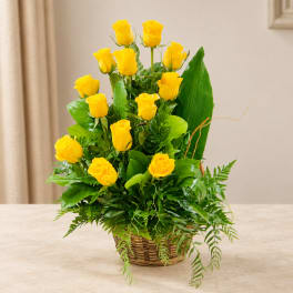 Yellow roses arranged in a wicker basket with greenery
