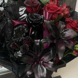 Bouquet of red and black roses with dark lilies in a glass vase