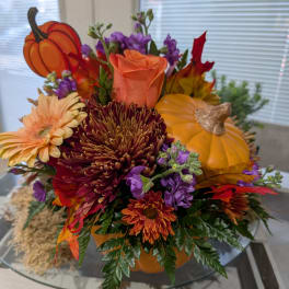 Fall floral arrangement with pumpkins, roses, and chrysanthemums