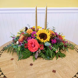 Colorful floral centerpiece with two tall gold candles