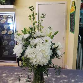 Tall white floral arrangement in a glass vase