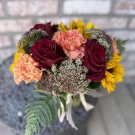 Bouquet of burgundy roses, peach carnations, and yellow flowers