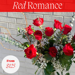 Tall vase arrangement of red roses with greenery and baby's breath