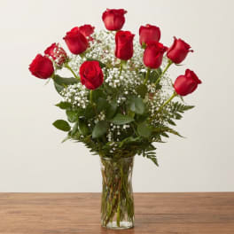Red roses arranged in a clear glass vase with white baby's breath