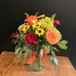Bouquet of orange and red roses with yellow daisies in a glass vase