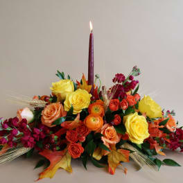Autumn floral centerpiece with a lit burgundy candle and mixed roses