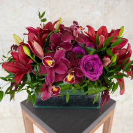 Magenta and red floral arrangement in a rectangular glass vase