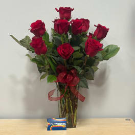 Red roses in a clear vase with a red ribbon bow