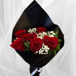 Bouquet of red roses with white filler flowers wrapped in black paper and ribbon