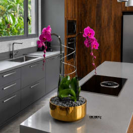 Pink orchid arrangement in a gold bowl on a kitchen island