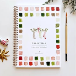 Christmas watercolor workbook with paint swatches and a brush