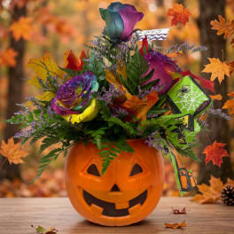 Halloween bouquet in a jack-o'-lantern container with colorful roses and autumn leaves