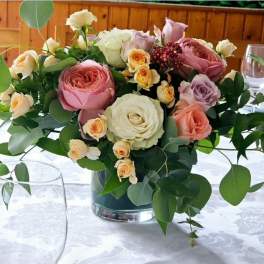 Mixed roses in a glass vase with greenery on a table